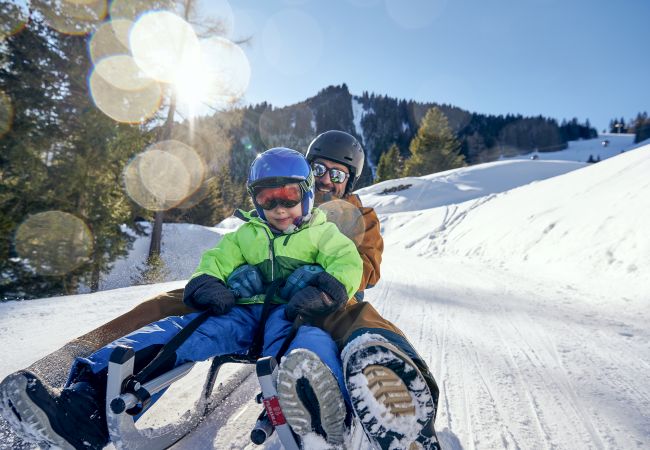 Vater rodelt mit Kind in Vorarlberg 